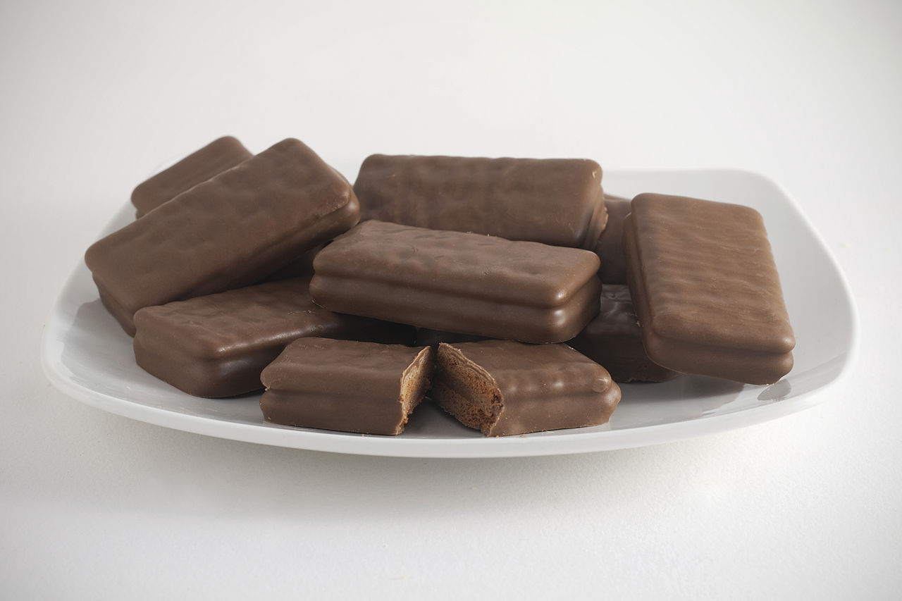 A plate of Tim Tams, with one in the centre broken open to show the biscuit and chocolate cream filling. Photograph by Bilby. Licensed under the Creative Commons Attribution-Share Alike 3.0 license.